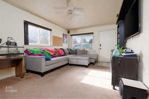 Living room with healthy amount of natural light, carpet floors, a ceiling fan, and a textured ceiling