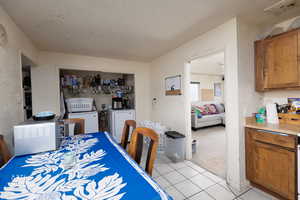 Dining space with light tile patterned flooring, light colored carpet, and washer and clothes dryer