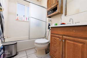 Bathroom featuring vanity, light tile patterned floors, and combined bath / shower with glass door