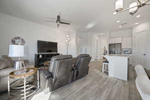 Living room with recessed lighting, light wood-style flooring, a ceiling fan, and a chandelier