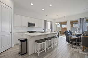 Kitchen with white cabinets, recessed lighting, an island with sink, appliances with stainless steel finishes, and hanging light fixtures
