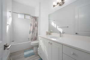 Full bathroom with shower / tub combo, vanity, and light wood-type flooring