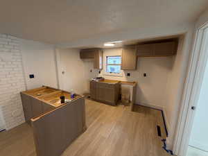 Kitchen with light wood finished floors, a textured ceiling, and brown cabinets
