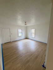 Empty room featuring a textured ceiling and light wood-style flooring