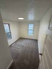 Spare room featuring a textured ceiling and dark carpet