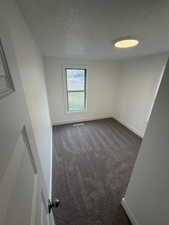 Spare room with a textured ceiling and dark colored carpet