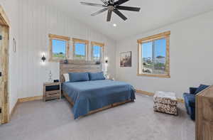 Carpeted bedroom featuring multiple windows, wooden walls, recessed lighting, vaulted ceiling, and ceiling fan