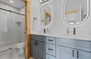 Bathroom with marble look tile flooring, double vanity, and a marble finish shower