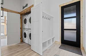 Laundry room with light wood-type flooring and estacked washer and dryer