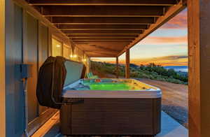 Patio terrace at dusk featuring a hot tub
