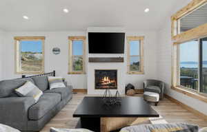 Living area featuring wood finished floors, recessed lighting, and a glass covered fireplace