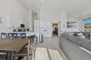 Dining space featuring light wood finished floors, recessed lighting, and high vaulted ceiling