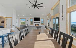 Dining space with a lit fireplace, light wood-type flooring, recessed lighting, and a ceiling fan