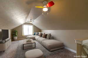 Carpeted living room featuring vaulted ceiling, a ceiling fan, and a textured ceiling