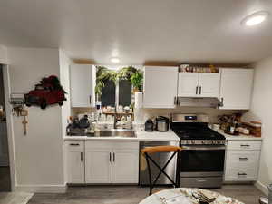 Kitchen featuring white cabinetry, stainless steel appliances, light countertops, light wood-style flooring, and a textured ceiling