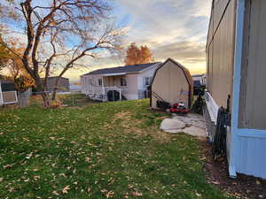 Back of property at dusk with a fenced backyard and a storage unit