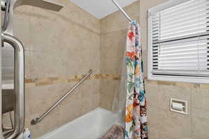Full bathroom with tile walls, vanity, light tile floors, and a tub/shower combo