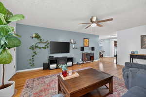 Living room featuring light paint, hardwood flooring, and a ceiling fan