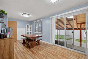 Dining area with light wood-style floors and backyard entrance