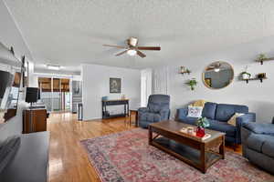 Living room featuring light paint, hardwood flooring, and a ceiling fan