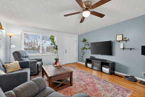 Living room featuring light paint, hardwood flooring, and a ceiling fan