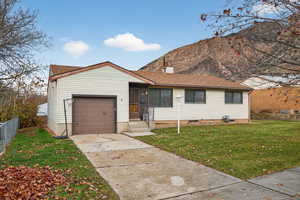 Single story home with concrete driveway, a shingled roof, and a mountain view