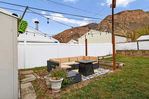 Fenced backyard featuring an outdoor living space with a fire pit, a patio area, and a mountain view