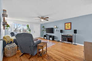 Living room featuring light paint, hardwood flooring, and a ceiling fan