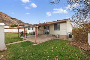 Rear view of house with a fully fenced backyard, covered patio, and mountain view