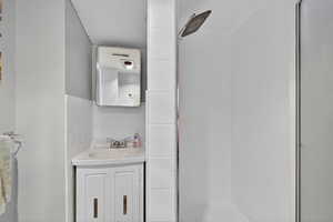 Basement bathroom with shower, tiled floors, and vanity