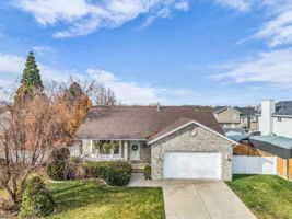 Single story home with driveway, a front lawn, an attached garage, and stone siding