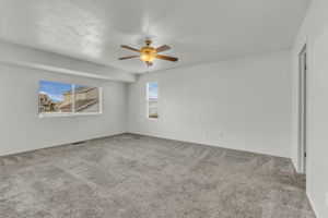 Primary bedroom featuring light carpet and a ceiling fan