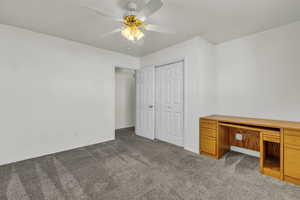 Unfurnished bedroom featuring carpet, a ceiling fan, a closet, and built in study area