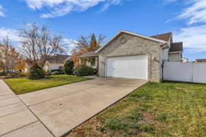 View of front of house featuring driveway, a garage, and stone siding