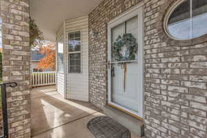 View of exterior entry with a porch and brick siding