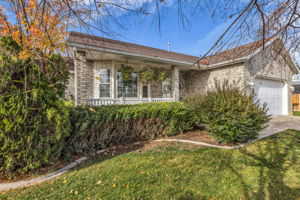 View of front of property with an attached garage, a front lawn, and covered porch