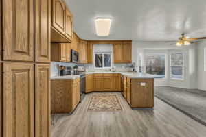 Kitchen with brown cabinets, a peninsula, light countertops, and a ceiling fan