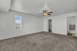 Unfurnished bedroom featuring a walk in closet, carpet floors, ceiling fan, and connected bathroom
