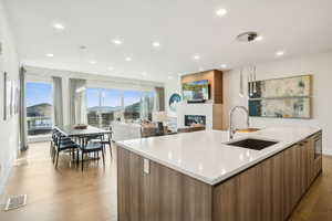 Kitchen with modern cabinets, brown cabinetry, a fireplace, a large island, and pendant lighting