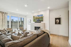 Living area with a premium fireplace, wood finished floors, and recessed lighting