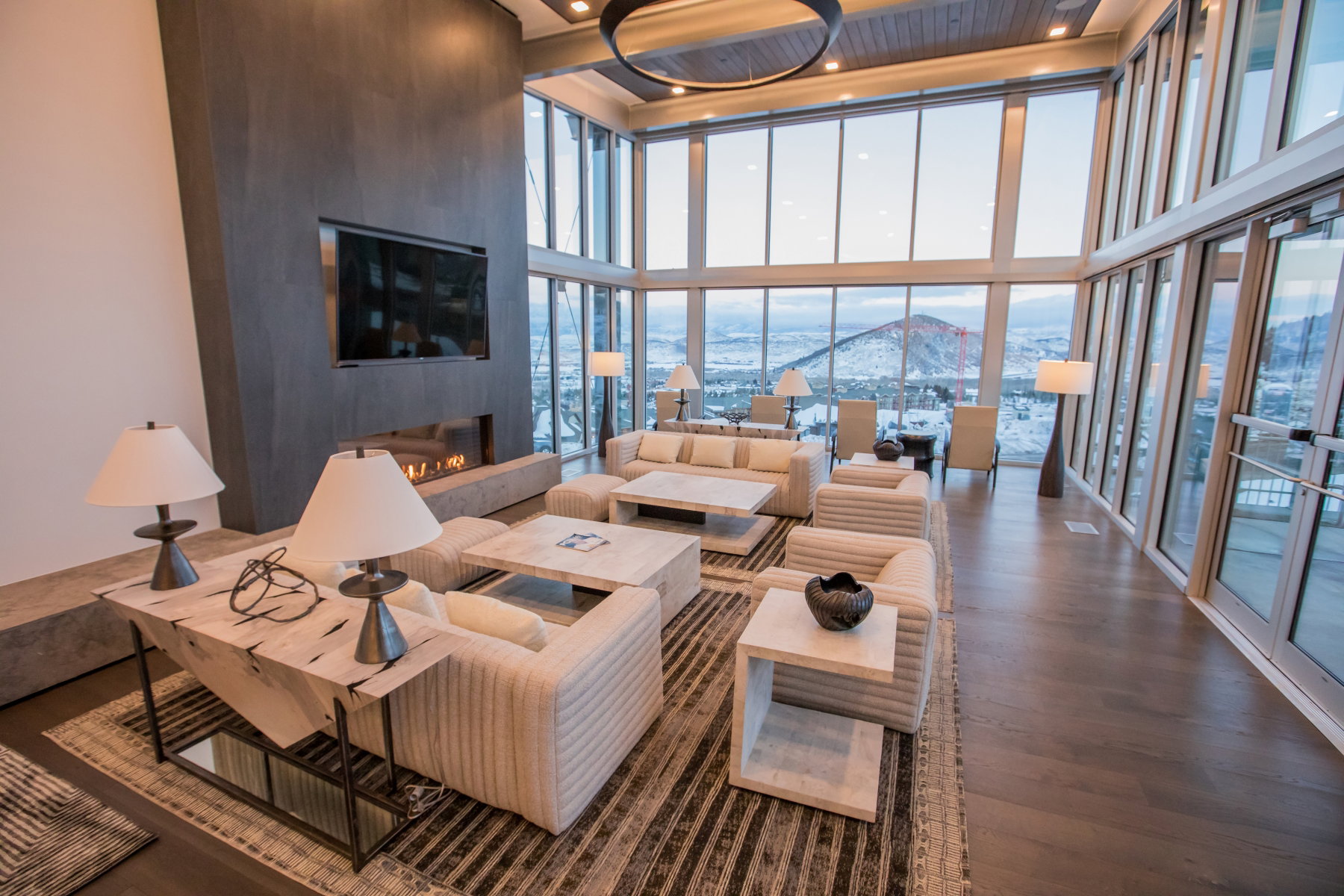Living room with a large fireplace, a wall of windows, a towering ceiling, recessed lighting, and wood finished floors