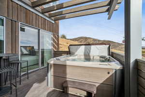 Wooden terrace featuring a hot tub and a mountain view
