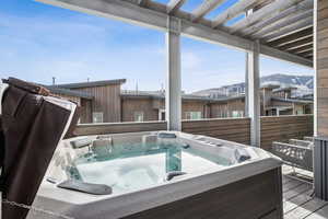 Wooden deck with a hot tub and a mountain view