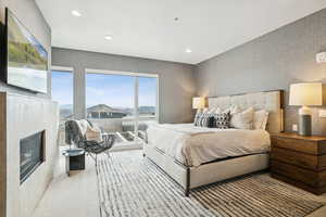 Carpeted bedroom featuring a glass covered fireplace, recessed lighting, and wallpapered walls