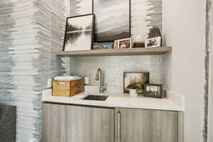 Bar with open shelves, modern cabinets, light brown cabinets, and light stone counters