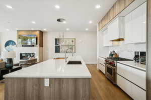 Kitchen featuring modern cabinets, pendant lighting, luxury stove, white cabinetry, and open floor plan