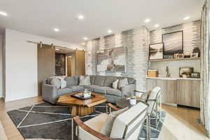 Living area with a barn door, light wood-style flooring, and recessed lighting