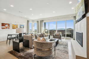 Living room with a lit fireplace, recessed lighting, and light wood-style floors