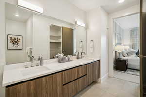 Ensuite bathroom with double vanity, light tile patterned floors, and recessed lighting