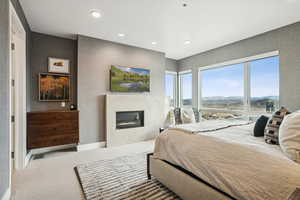 Carpeted bedroom featuring a glass covered fireplace and recessed lighting